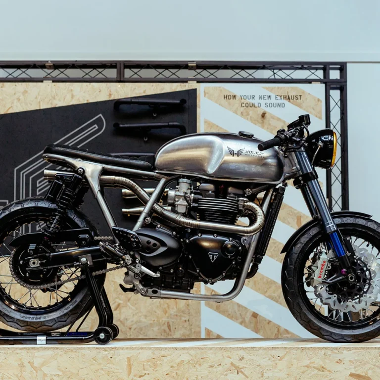 A custom Triumph Thruxton on a workshop stand, its stainless headers, engine cases and polished tank on show