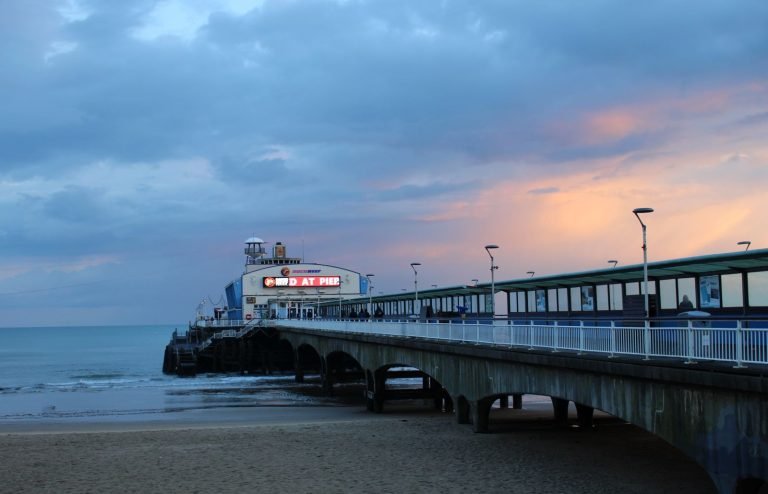 Bournemouth Pier reaching out over the beach at dusk, pink light behind the cloud