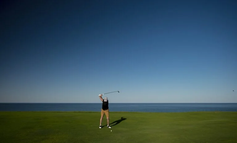 Four golfers walking a fairway carrying clubs