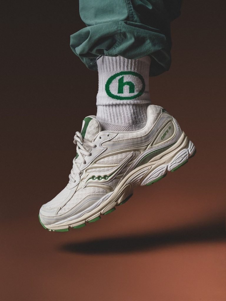 A preloved white Saucony ProGrid trainer photographed against a warm brown backdrop for the Footprint Shoes homepage